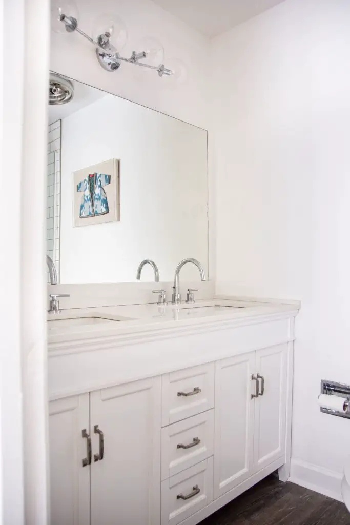 White bathroom renovation with new vanity, faucets, and lighting on Thou Swell #bathroom #bathroomdesign #whitebathroom #masterbathroom